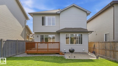 Expansive grassy yard area with a wooden deck, sliding glass door, and a paved patio - 4610 Westcliff Point(E) Sw, Edmonton, AB 