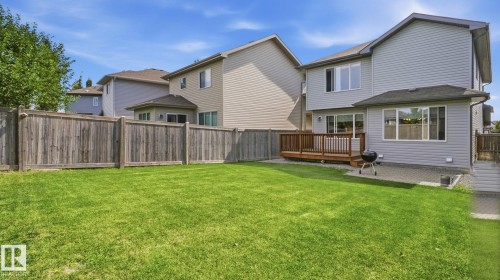 Expansive backyard with a manicured lawn, wood privacy fence, and a spacious wood deck - 4610 Westcliff Point(E) Sw, Edmonton, AB 