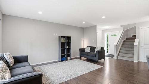 Recessed lighting, wood-finish flooring, staircase with white railing, paneled interior door, and neutral wall tones - 4610 Westcliff Point(E) Sw, Edmonton, AB 