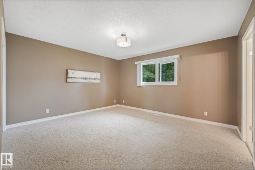 Carpeted room featuring a single window and a semi-flush ceiling light fixture - 5502 45 Street, Stony Plain, AB - Indoor Photo Showing Other Room