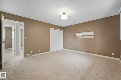Spacious room featuring neutral paint, light-colored carpet, a ceiling-mounted light fixture, and white bi-fold closet doors - 5502 45 Street, Stony Plain, AB - Indoor Photo Showing Other Room