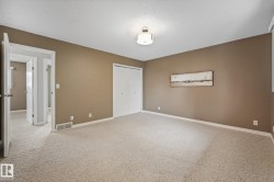 Spacious room featuring neutral paint, light-colored carpet, a ceiling-mounted light fixture, and white bi-fold closet doors - 