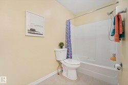 Bathroom featuring a white toilet, white bathtub with a shower, and light-toned wall paint - 
