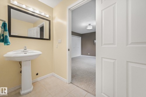 Pedestal sink with chrome faucet, framed mirror, and vanity lighting - 5502 45 Street, Stony Plain, AB - Indoor Photo Showing Bathroom