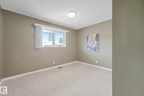 Carpeted room featuring a white-framed window, neutral painted walls, white baseboards, and a flush-mount ceiling light fixture - 5502 45 Street, Stony Plain, AB - Indoor Photo Showing Other Room