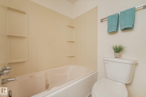 Bathtub with integrated shelving, chrome fixtures, and a white toilet - 5502 45 Street, Stony Plain, AB - Indoor Photo Showing Bathroom