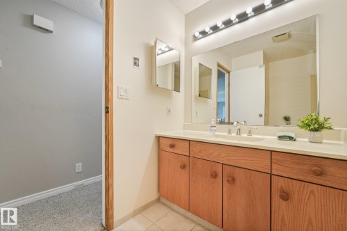 Bathroom featuring a light wood-finish vanity with ample storage, a white countertop, and a large wall-mounted mirror - 5502 45 Street, Stony Plain, AB - Indoor Photo Showing Bathroom