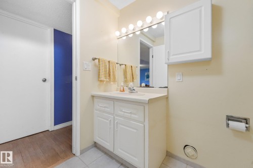 Bathroom vanity featuring white cabinetry, an integrated sink, and a mirrored medicine cabinet - 5502 45 Street, Stony Plain, AB - Indoor Photo Showing Bathroom