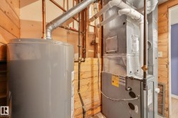 Mechanical room featuring a water heater, furnace, and exposed copper and galvanized piping - 