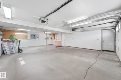 Spacious garage featuring a concrete floor, multiple fluorescent light fixtures, an automatic garage door opener, and interior access doors - 