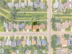 Aerial perspective highlighting a residential property with a brown roof and a green lawn - 