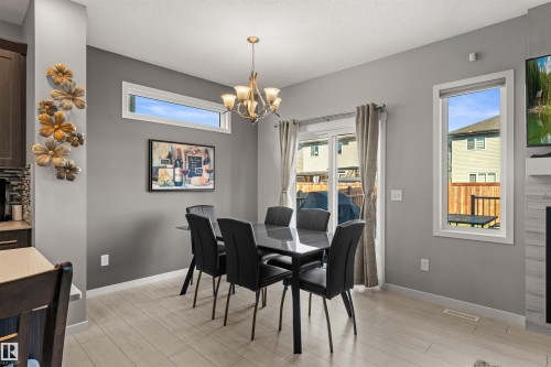 Wood-finish flooring throughout, complemented by a contemporary chandelier - 12218 176 Avenue Nw, Edmonton, AB 