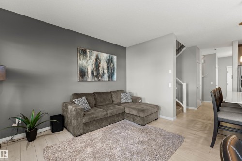 Wood-finish flooring throughout, featuring a staircase with white risers and dark treads, and a kitchen with stainless steel appliances - 12218 176 Avenue Nw, Edmonton, AB 