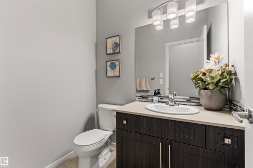 Dark wood-finish vanity with a light-toned countertop, oval undermount sink, and a multi-shade tile backsplash - 12218 176 Avenue Nw, Edmonton, AB 