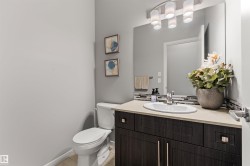Dark wood-finish vanity with a light-toned countertop, oval undermount sink, and a multi-shade tile backsplash - 