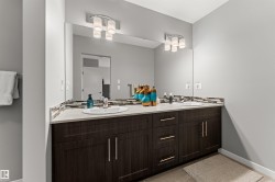 Dual vanity featuring integrated sinks, a continuous mirror, and under-cabinet storage with contemporary hardware - 