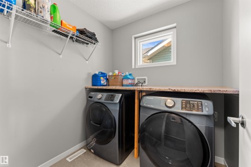 Dedicated laundry area featuring a built-in countertop, wall-mounted wire shelving, and a white framed window - 12218 176 Avenue Nw, Edmonton, AB 
