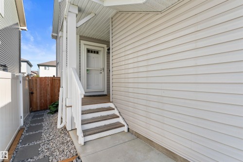 Front entry with covered porch, white siding exterior, and wood steps with white railings - 12218 176 Avenue Nw, Edmonton, AB 