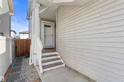 Front entry with covered porch, white siding exterior, and wood steps with white railings - 