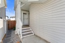 Front entry with covered porch, white siding exterior, and wood steps with white railings - 12218 176 Avenue Nw, Edmonton, AB 