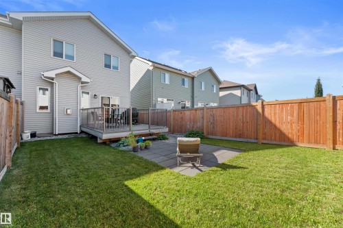 Well-maintained backyard featuring a wood deck, concrete paver patio, wood fencing, and a manicured lawn - 12218 176 Avenue Nw, Edmonton, AB 