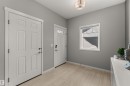 Light wood-finish flooring, neutral gray wall tones, white trim, recessed lighting, and a transom window above the entry door - 12218 176 Avenue Nw, Edmonton, AB 