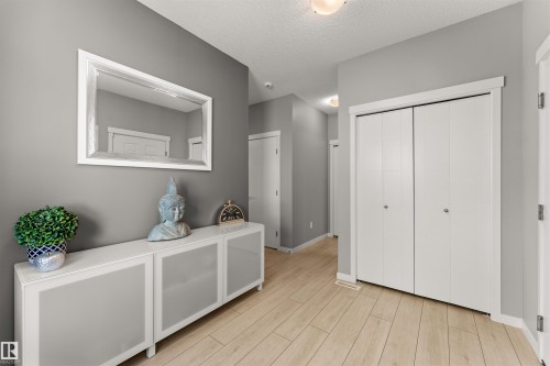 Wood-finish flooring, white bi-fold closet doors, white trim, and a white console cabinet with frosted glass panels - 12218 176 Avenue Nw, Edmonton, AB 