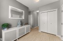 Wood-finish flooring, white bi-fold closet doors, white trim, and a white console cabinet with frosted glass panels - 12218 176 Avenue Nw, Edmonton, AB 