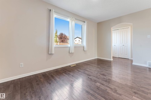 Hardwood-style flooring throughout, dual windows with white trim, arched entryway, and bi-fold closet doors - 1124 37A Avenue Nw, Edmonton, AB 