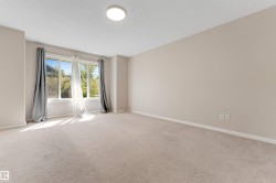 Bright, sun-filled bedroom featuring neutral wall finishes, plush carpeting, recessed ceiling lighting, and glass sliding doors with custom drapery opening to outdoor space - 