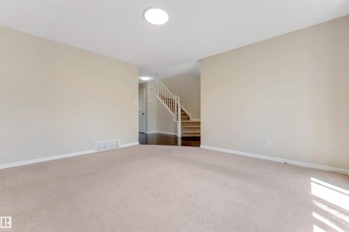 Carpeted living area with light-toned walls, recessed ceiling lighting, and a staircase featuring wood-finish treads and white risers - 1124 37A Avenue Nw, Edmonton, AB 