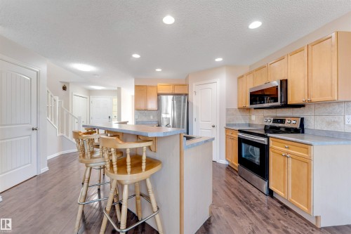 Kitchen featuring wood-finish flooring, light wood cabinetry, stainless steel appliances, a tiled backsplash, and recessed lighting - 1124 37A Avenue Nw, Edmonton, AB 