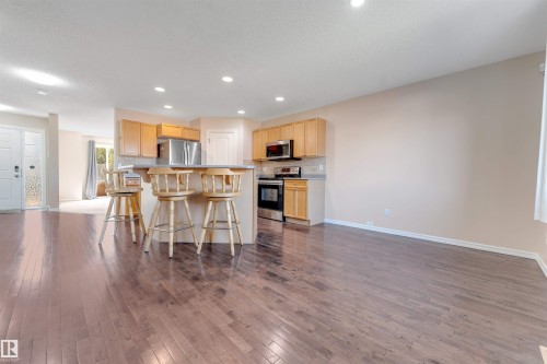 Hardwood flooring throughout, kitchen featuring light wood cabinetry, stainless steel appliances, and recessed lighting - 1124 37A Avenue Nw, Edmonton, AB 