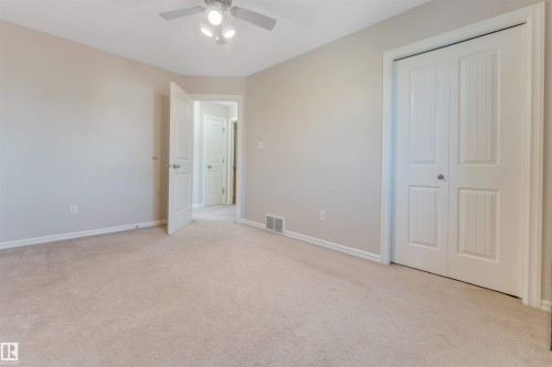 Neutral-toned carpet flooring, a ceiling-mounted light fixture with fan, and a bi-fold closet door - 1124 37A Avenue Nw, Edmonton, AB 