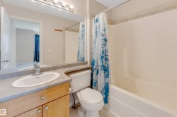 Vanity with wood-finish cabinetry, solid surface countertop, and integral sink - 