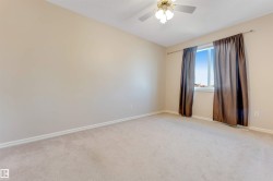 Neutral tone wall paint, light-colored carpet flooring, a window with drapery rods, and a ceiling fan with integrated lighting - 