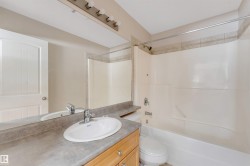 Bathroom featuring a vanity with wood cabinetry, an integrated sink, and a large mirror - 