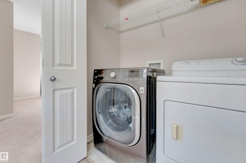 Laundry area featuring a front-load washer, a top-load dryer, and an overhead wire shelf - 1124 37A Avenue Nw, Edmonton, AB 