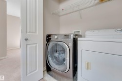 Laundry area featuring a front-load washer, a top-load dryer, and an overhead wire shelf - 