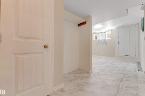 White interior door with brass knob, light-toned wall paint, marble-finish floor tiles, and recessed ceiling lighting - 1124 37A Avenue Nw, Edmonton, AB 