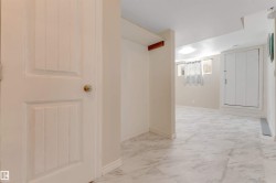 White interior door with brass knob, light-toned wall paint, marble-finish floor tiles, and recessed ceiling lighting - 