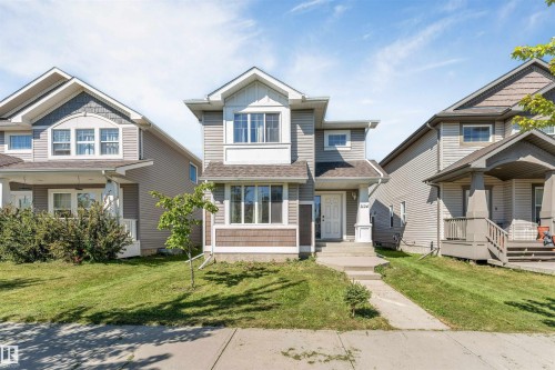 Two-story residence featuring light gray horizontal siding, dark brown shingle siding accents, white trim, and a concrete walkway - 1124 37A Avenue Nw, Edmonton, AB 