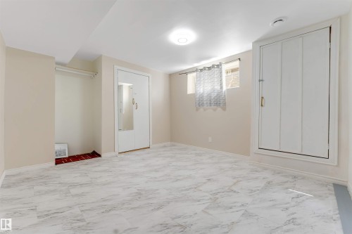 Spacious room featuring light-toned walls, a flush-mount ceiling light, and light-toned, patterned floor tiles - 1124 37A Avenue Nw, Edmonton, AB 