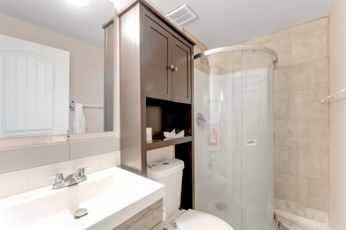 Integrated vanity with a rectangular sink, wall-mounted mirror, and wood-finish cabinetry - 1124 37A Avenue Nw, Edmonton, AB 