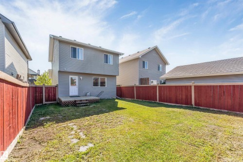 Spacious rear yard with a wooden privacy fence, a ground-level deck, and a two-story residence featuring siding - 1124 37A Avenue Nw, Edmonton, AB 