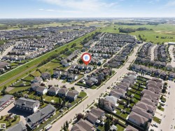 Residential subdivision with varied architectural styles, bordered by open fields and a linear green space - 