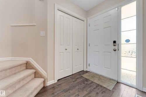 Entryway featuring wood-finish flooring, a paneled front door with a digital lock, and a decorative side window - 1124 37A Avenue Nw, Edmonton, AB 