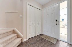 Entryway featuring wood-finish flooring, a paneled front door with a digital lock, and a decorative side window - 