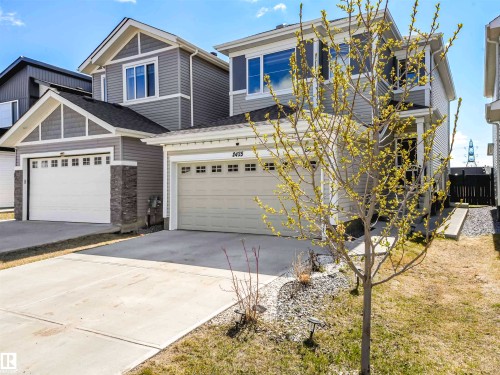 Gray siding exterior featuring a front-facing garage with window inserts, and concrete driveway - 2435 12 Avenue Nw, Edmonton, AB 
