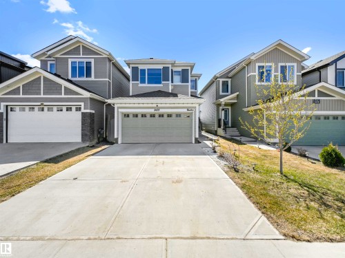 Two-story residence featuring light gray siding, an attached two-car garage, and a concrete driveway - 2435 12 Avenue Nw, Edmonton, AB 